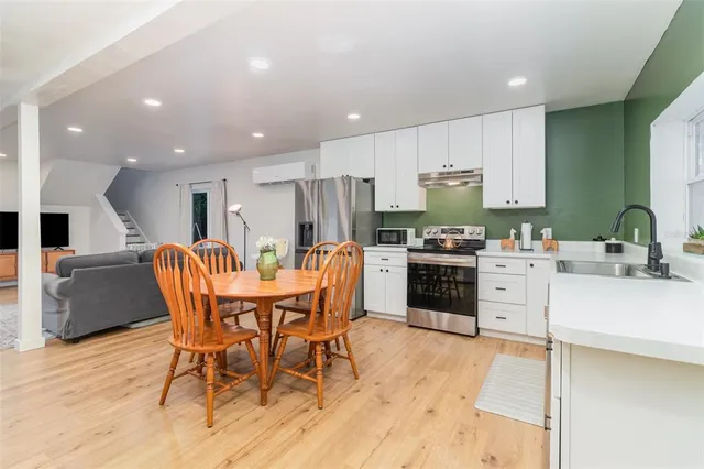 a kitchen with stainless steel appliances a stove a sink a kitchen island with a dining table and chairs