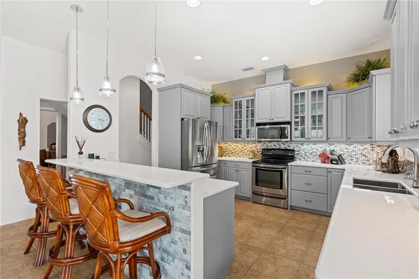 a kitchen with stainless steel appliances granite countertop a sink a stove a refrigerator cabinets and chairs