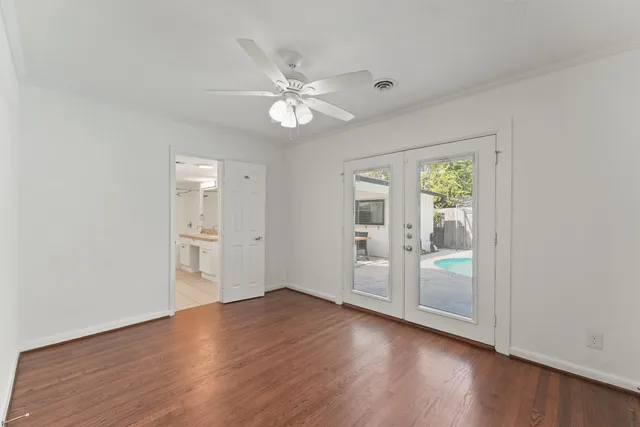 an empty room with wooden floor fan and windows