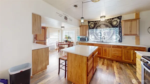 a living room with kitchen island granite countertop wooden floor and a sink