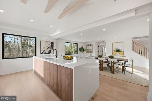 a large white kitchen with stainless steel appliances granite countertop a stove and living room view
