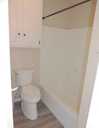 an empty room with wooden floor cabinet and windows