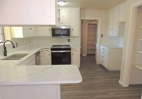 a kitchen with a refrigerator sink and white cabinets