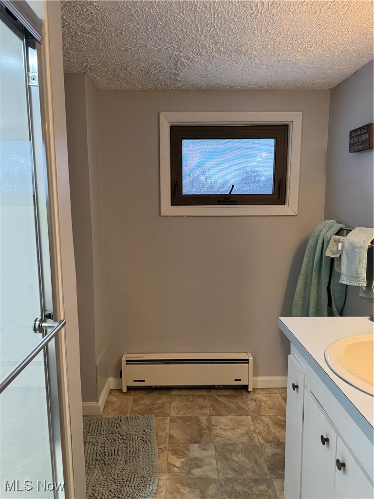 2644 Harpster Road Rittman, OH 44270 - Photo 16 of 20 Second floor full bath with vanity, walk-in shower, a baseboard radiator, and a textured ceiling