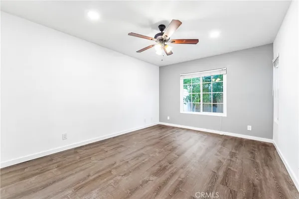 an empty room with wooden floor fan and windows