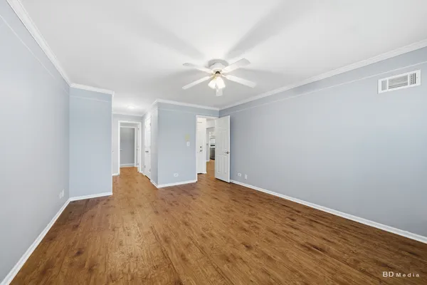a view of empty room with wooden floor and fan