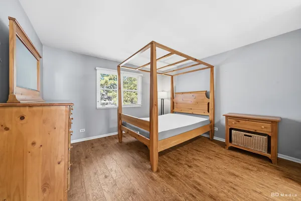 a bedroom with wooden floor and window