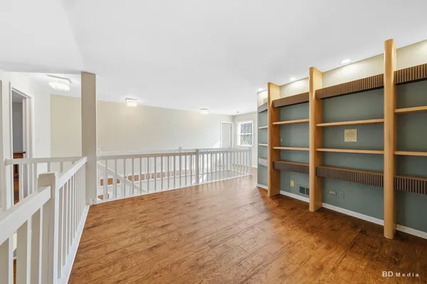 a view of an empty room with wooden floor and windows