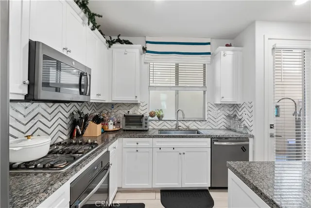 a kitchen with stainless steel appliances granite countertop a sink stove and cabinets