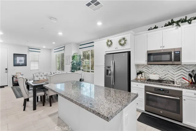 a kitchen with stainless steel appliances granite countertop a stove top oven a sink a dining table and chairs