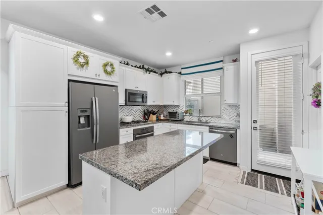 a kitchen with stainless steel appliances granite countertop a refrigerator a sink a stove a microwave and island