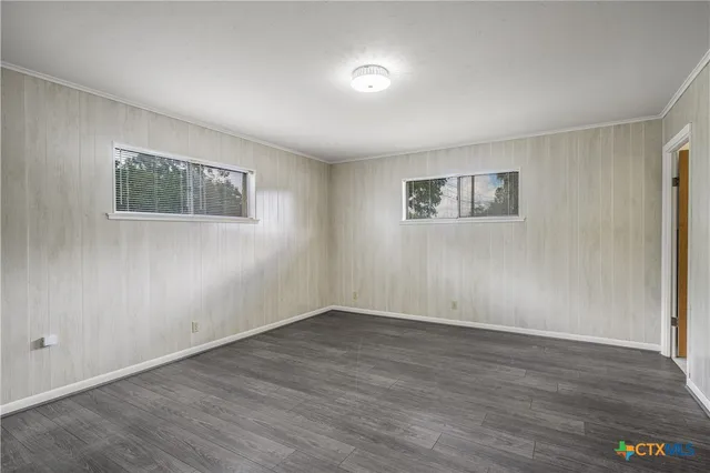 a view of an empty room with wooden floor and a painting