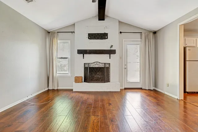 a view of a livingroom with wooden floor and a fireplace