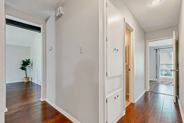 a view of a hallway with wooden floor and a bathroom