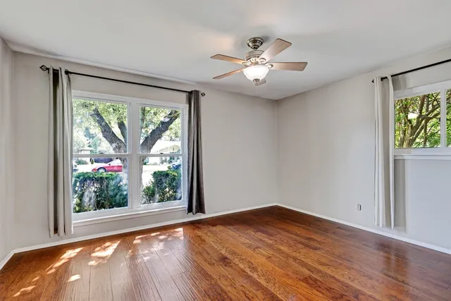a view of an empty room with wooden floor and a window
