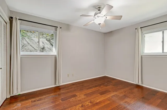 a view of empty room with wooden floor and fan