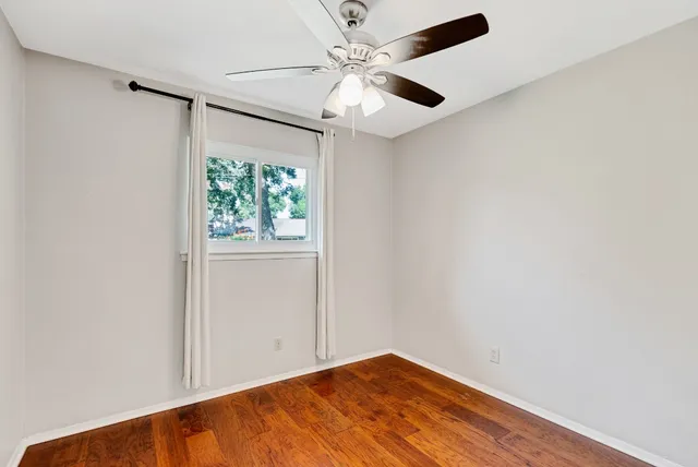 an empty room with windows and fan