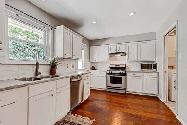 a kitchen with cabinets stainless steel appliances a sink and window