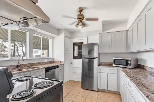 a kitchen with stainless steel appliances granite countertop a sink a stove a refrigerator cabinets and dining table