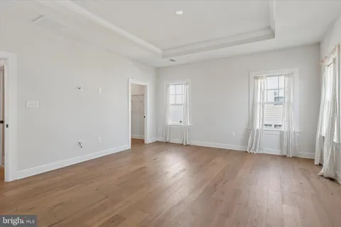 a view of an empty room with wooden floor and closet