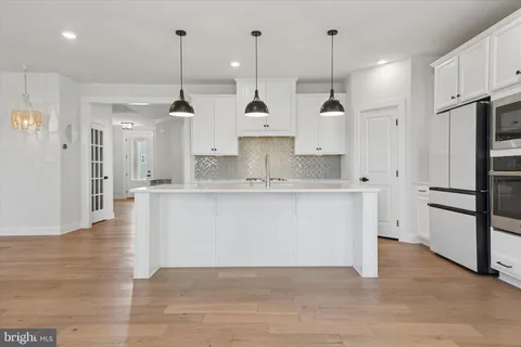 a large kitchen with stainless steel appliances kitchen island wooden cabinets and a fireplace