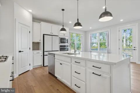 a kitchen with stainless steel appliances kitchen island granite countertop a stove a refrigerator and a sink with wooden floor