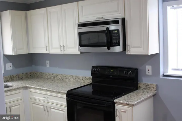a kitchen with granite countertop white cabinets and a stove top oven