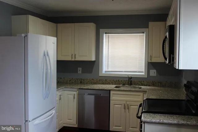 a kitchen with granite countertop white cabinets and refrigerator
