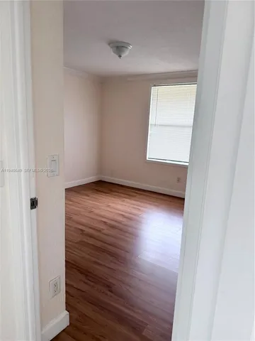 an empty room with wooden floor cabinet and windows