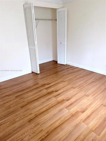 an empty room with wooden floor and entrance