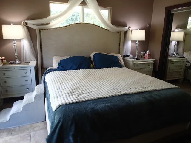 a large bedroom with a bed and a mirror on dresser