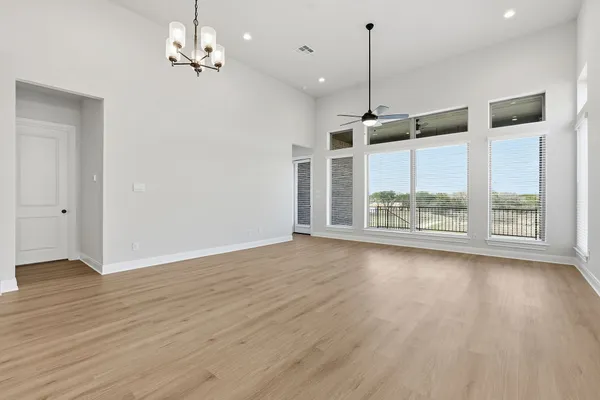 an empty room with wooden floor a ceiling fan and windows