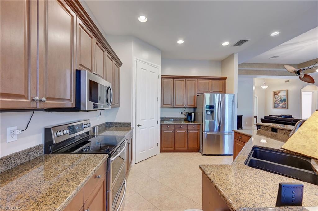 12518 Grandezza Circle Estero, FL 33928 - Photo 9 of 33 a kitchen with stainless steel appliances granite countertop a refrigerator stove microwave and sink