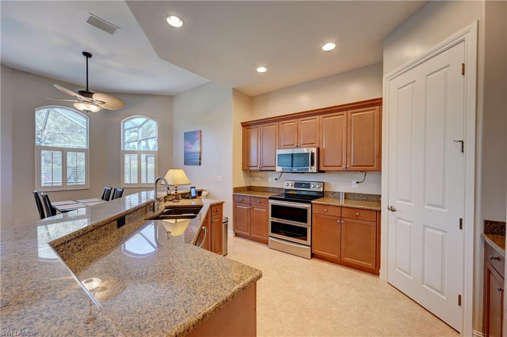 12518 Grandezza Circle Estero, FL 33928 - Photo 10 of 33 a large kitchen with stainless steel appliances granite countertop a sink dishwasher stove and refrigerator