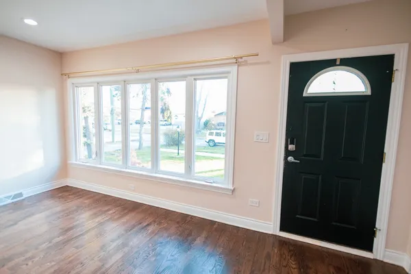 an empty room with wooden floor cabinet and windows