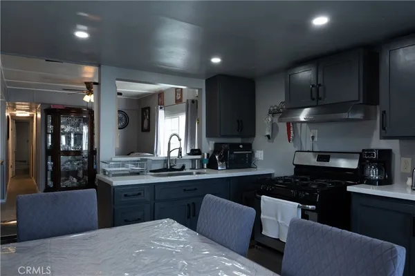a kitchen with granite countertop a sink a stove top oven and cabinets