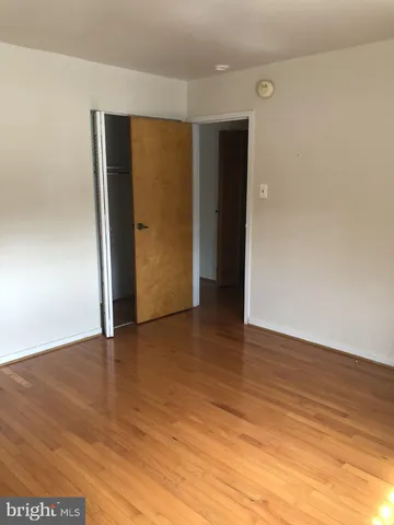 a view of an empty room with wooden floor and closet