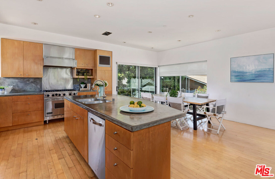 32 Fleet Street Marina del Rey, CA 90292 - Photo 8 of 39 a kitchen with stainless steel appliances granite countertop a stove top oven a dining table and chairs with wooden floor