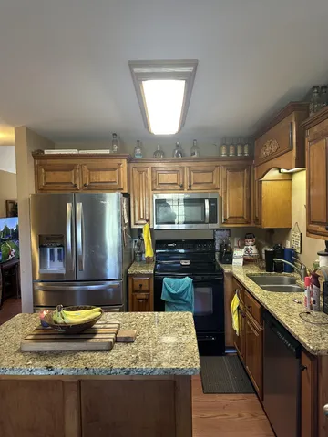 a kitchen with kitchen island granite countertop a sink stove and refrigerator