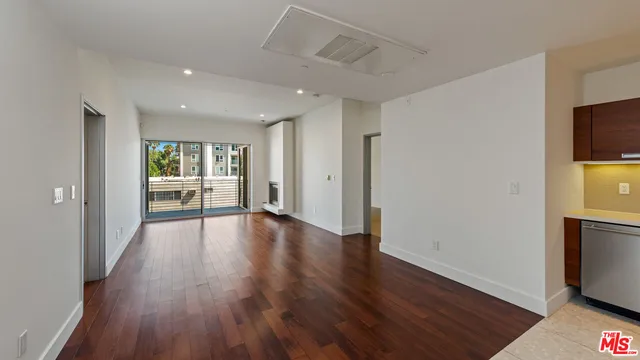 a view of a big room with wooden floor and windows