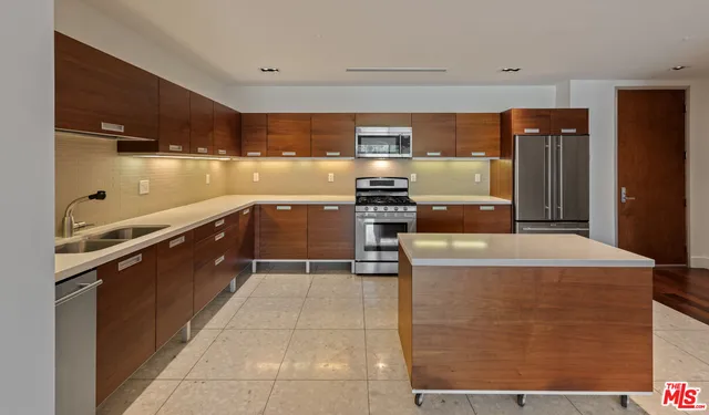 a kitchen with stainless steel appliances granite countertop a stove top oven a sink dishwasher and a refrigerator