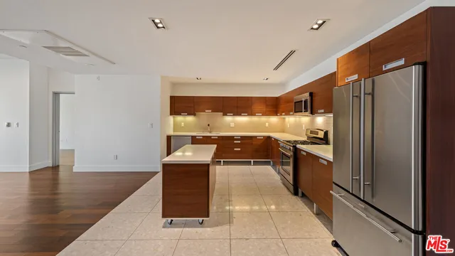 a kitchen with kitchen island granite countertop a refrigerator and a sink
