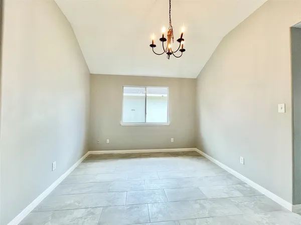 an empty room with a chandelier fan and windows