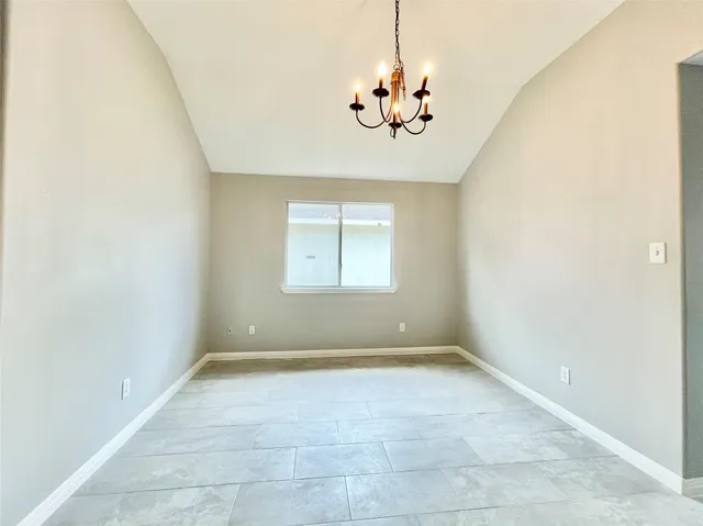 an empty room with a chandelier fan and windows