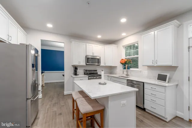 a kitchen with a refrigerator a sink cabinets and wooden floor