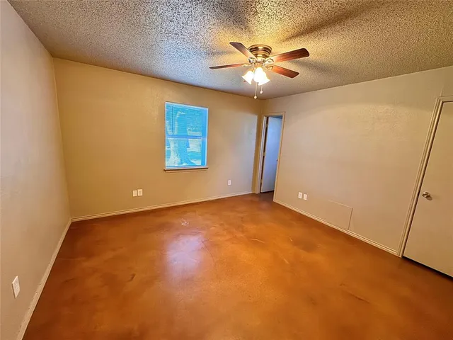 an empty room with a chandelier fan and windows