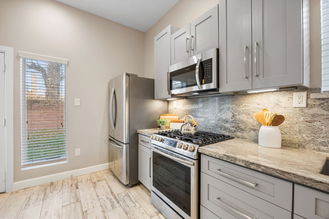 317 East 35th Street, Unit A Houston, TX 77018 - Photo 9 of 24 a kitchen with granite countertop wooden cabinets stainless steel appliances and a window