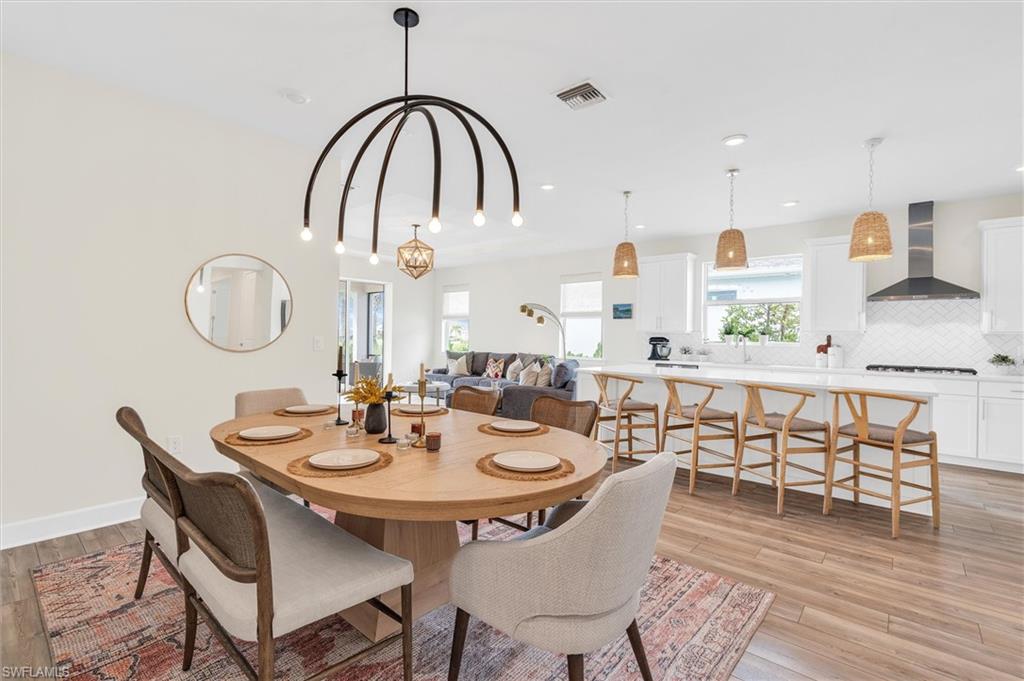 42322 Edgewater Drive Babcock Ranch, FL 33982 - Photo 12 of 40 a dining room with wooden floor a chandelier a wooden table and chairs