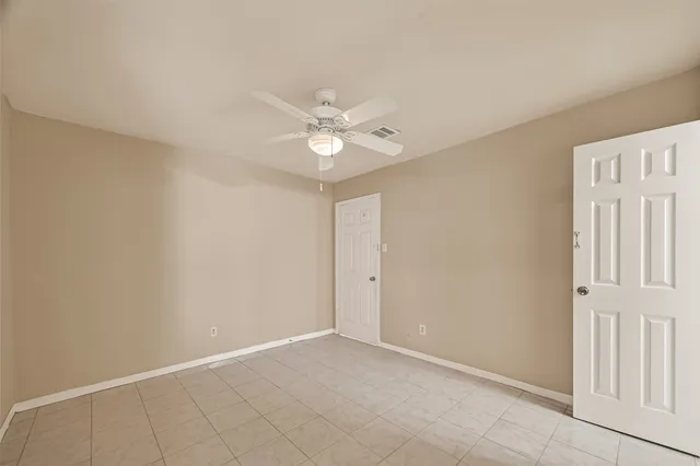 an empty room with windows and ceiling fan