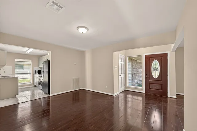an empty room with wooden floor and windows